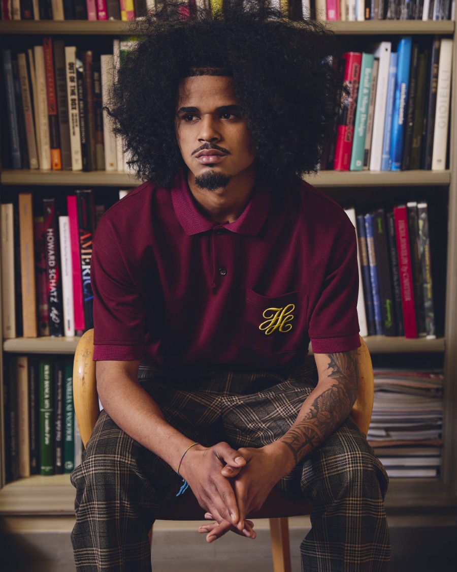IH NOM UH NIT FW26 burgundy short-sleeve polo shirt with yellow embroidered monogram on chest pocket, front view.