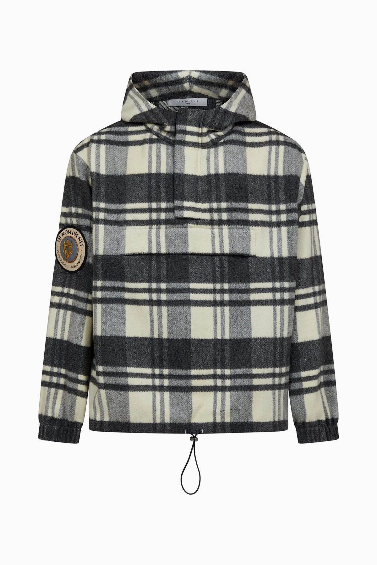IH NOM UH NIT FW26 cream, grey and black checked anorak with hood, monogram sleeve patch and adjustable drawstring hem, front view.
