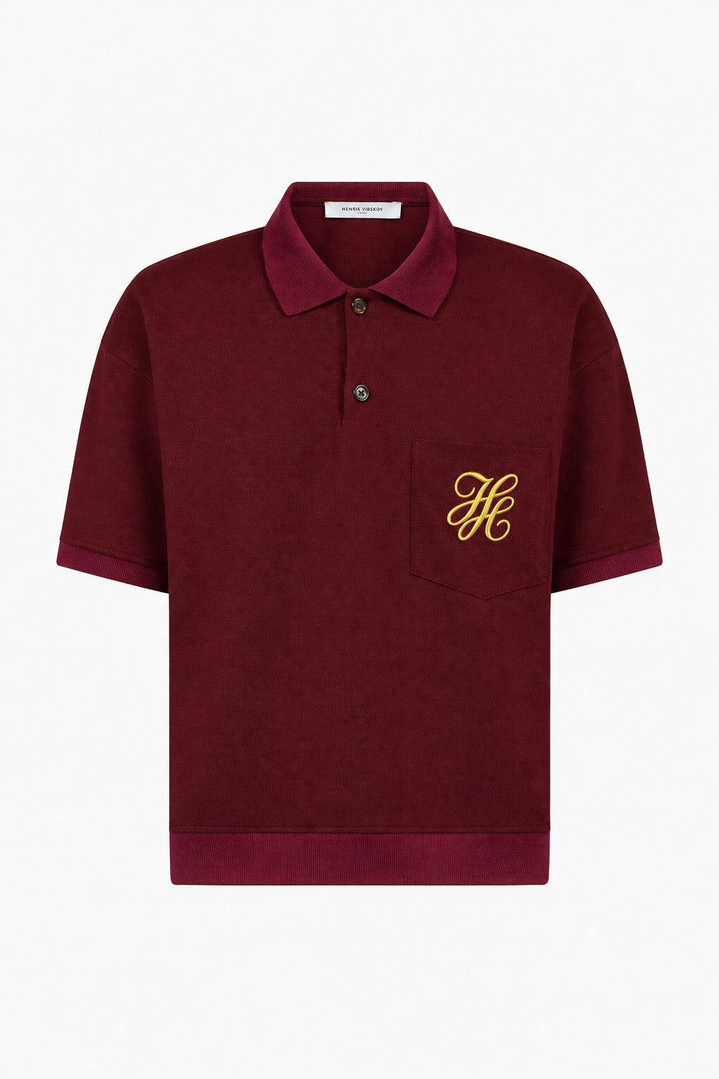 IH NOM UH NIT FW26 burgundy short-sleeve polo shirt with yellow embroidered monogram on chest pocket, front view.